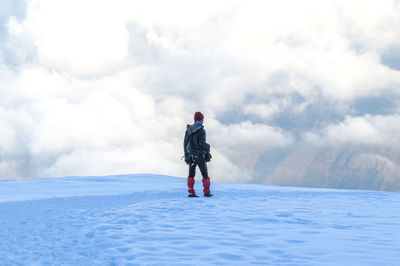 Rear view of man standing on snow against sky