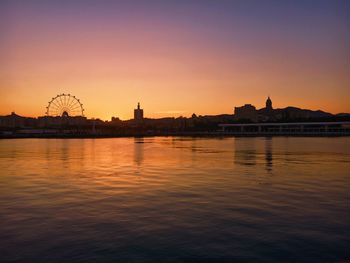 Silhouette of buildings in city at sunset