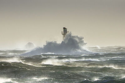 Lighthouse by sea against clear sky