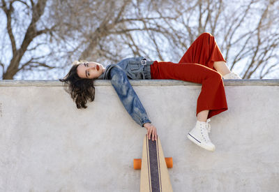 Woman lying down on snow covered tree