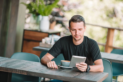 Man using mobile phone while sitting on table