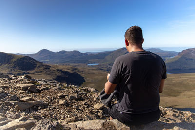 Rear view of man looking at mountains against sky