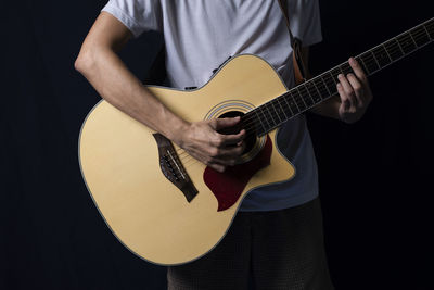 Midsection of man playing guitar