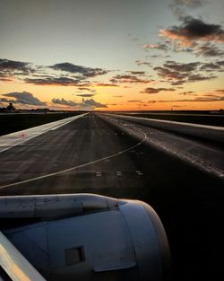 Airplane wing against sky during sunset