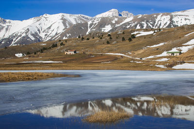 Scenic view of lake by snowcapped mountains against sky