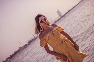 Portrait of woman wearing sunglasses while standing at beach