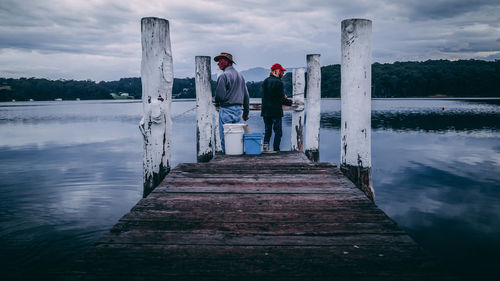 People standing by lake against sky