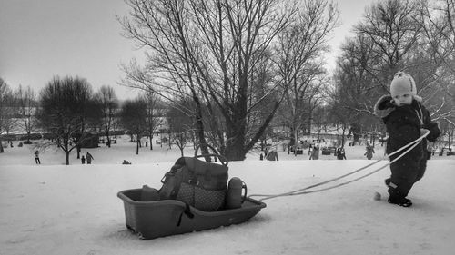 People on snowy field against sky during winter