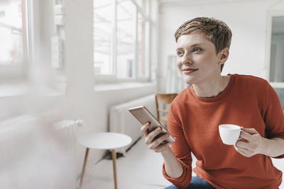 Smiling woman with cell phone and espresso cup