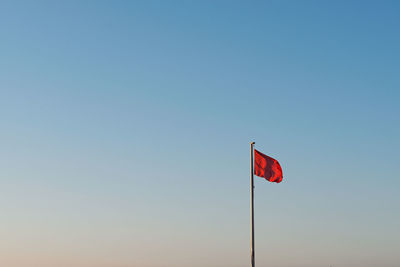 Low angle view of flag against clear blue sky