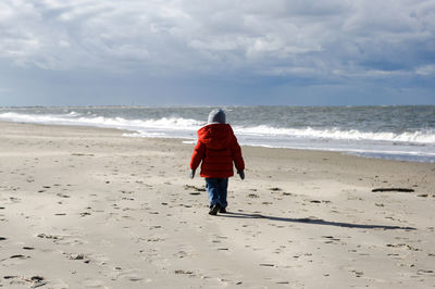 Rear view of girl at beach during winter