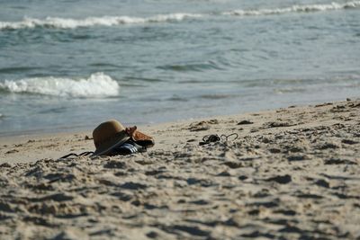 Hat and shoes on sand at beach