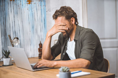 Young man using laptop at desk in office