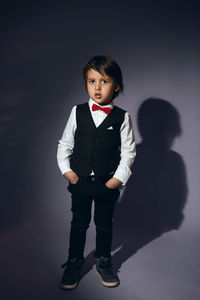 Stylish boy child of four years in the studio on the background in a vest and a red bow tie