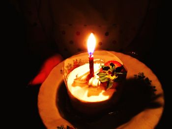 Close-up of lit candle in plate