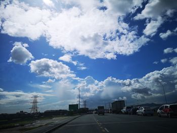 Cars on highway in city against sky