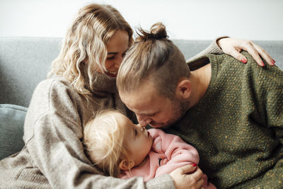 Woman embracing man and girl rubbing noses at home