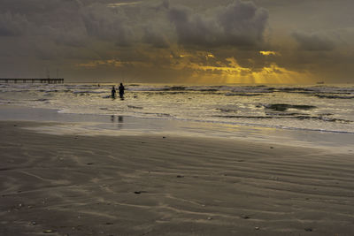 Silhouette person standing on beach against sky during sunset