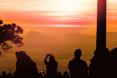 Silhouette people against orange sky