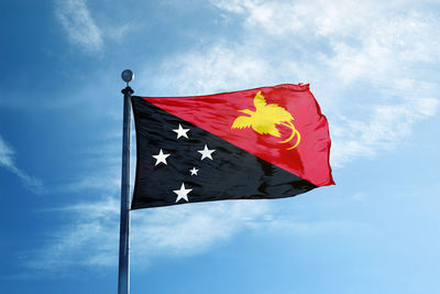 Low angle view of flag against blue sky