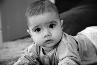 Portrait of cute baby boy lying on bed at home