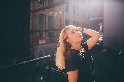 Close-up of young woman standing against wall in city