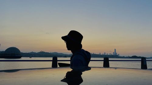 Rear view of man in river against sky during sunset
