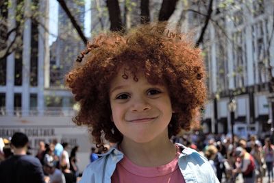 Portrait of boy with curly hair smiling in city