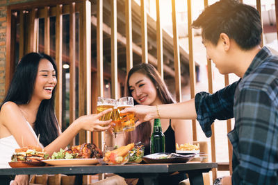 Cheerful friends toasting beer glasses at table in restaurant