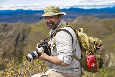 Midsection of man photographing against mountain range