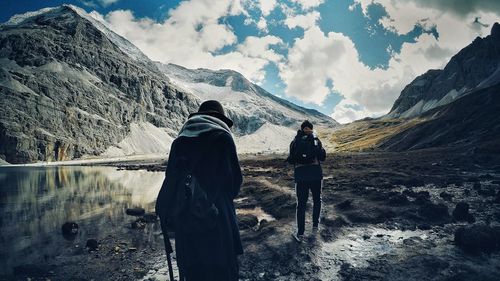 Rear view of men on mountain against sky
