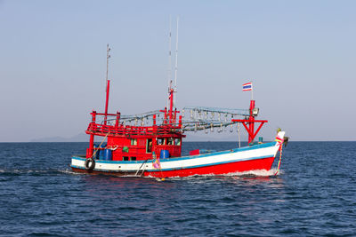 Fishing boat in sea against clear sky