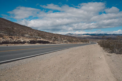 Scenic view of road by mountains against sky