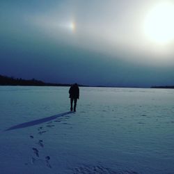 Silhouette of person in sea against sky during winter