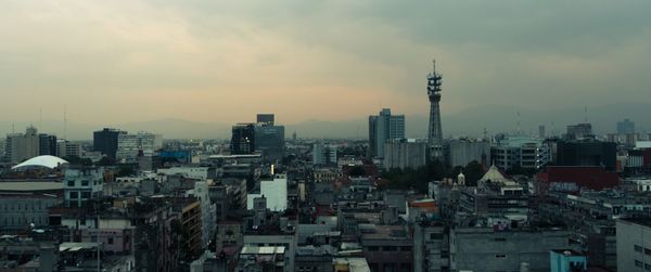 Panoramic view of buildings in city against cloudy sky