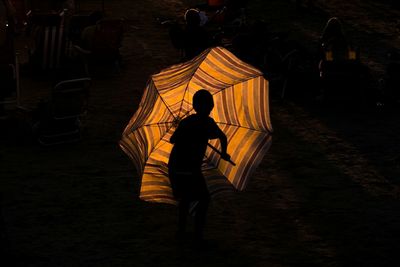 Rear view of boy standing at night