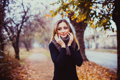 Portrait of woman standing by tree during autumn
