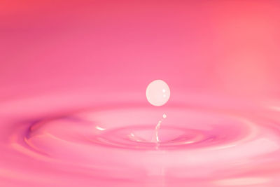 Close-up of water splashing against pink background