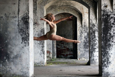 Full length of woman dancing in corridor of abandoned building