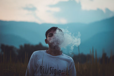 Man smoking cigarette against sky