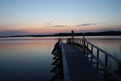 Silhouette pier on lake against sky during sunset