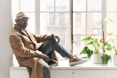 Full length portrait of man sitting by window