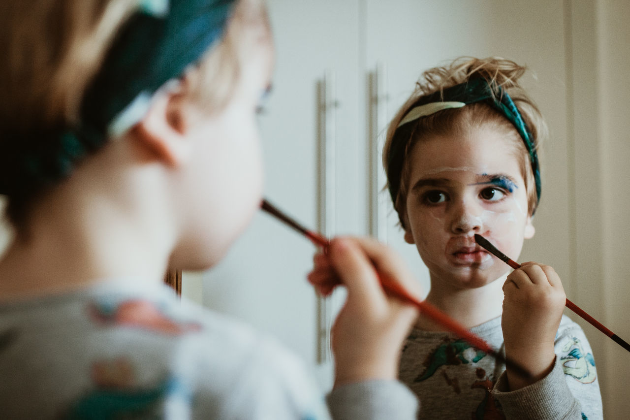 Close-up of girl painting her face in home