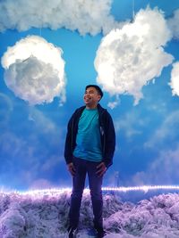 Digital composite image of young man standing by clouds