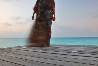 Man standing on pier over sea against sky