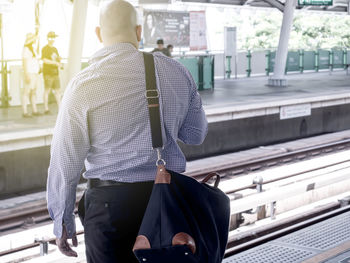 Rear view of man walking with umbrella in city