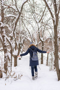 Full length rear view of person walking on snow covered field