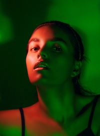 Close-up portrait of woman in green light