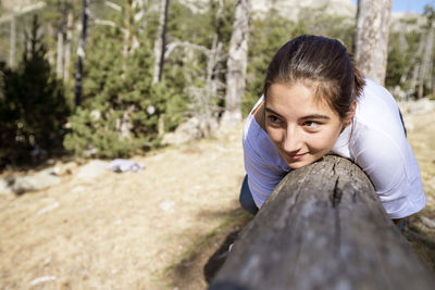 Portrait of woman sitting on tree trunk in forest