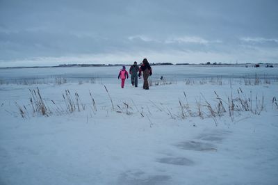 People on shore against sky during winter